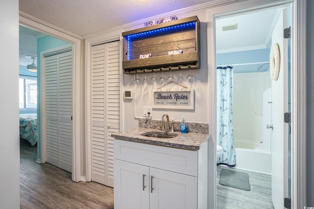 6000 N Ocean Blvd Unit 133, North Myrtle Beach, SC 29582 - indoor wet bar with crown molding, wood finished floors, and a textured ceiling