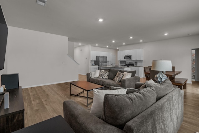 living room with recessed lighting, baseboards, and light wood-style floors