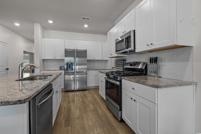 kitchen featuring stainless steel appliances, a sink, tasteful backsplash, white cabinets, and recessed lighting