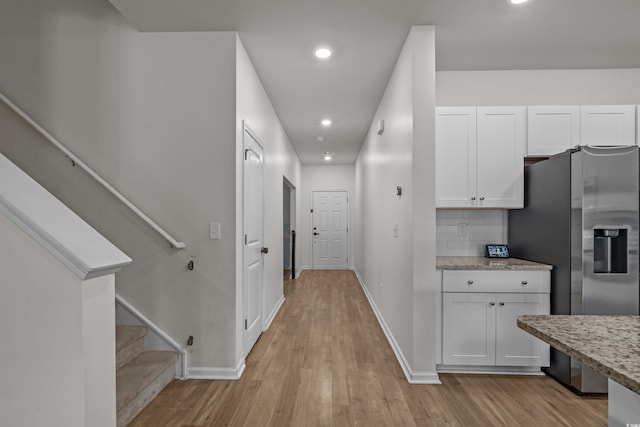 corridor with stairway, light wood-style floors, baseboards, and recessed lighting