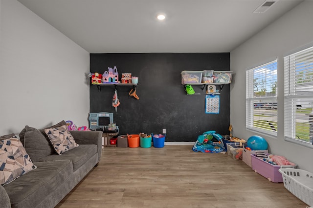 rec room with wood finished floors, an accent wall, and recessed lighting