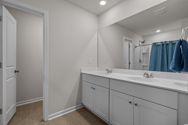 bathroom featuring curtained shower, double vanity, baseboards, and recessed lighting