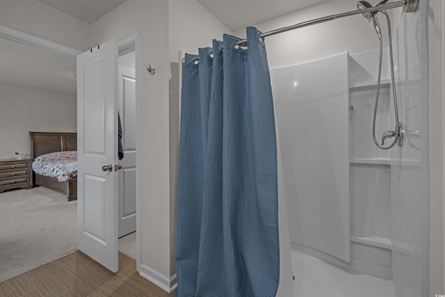 bathroom with a shower with shower curtain, ensuite bath, wood finished floors, and baseboards
