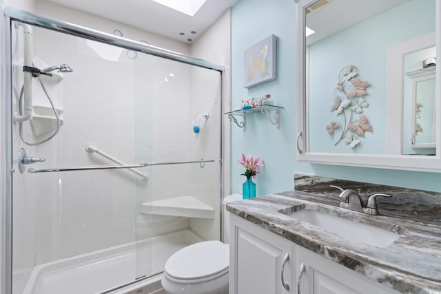 bathroom with toilet, a shower stall, vanity, and a skylight