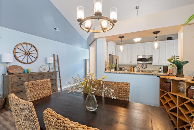 dining area featuring a chandelier, wood finished floors, and high vaulted ceiling