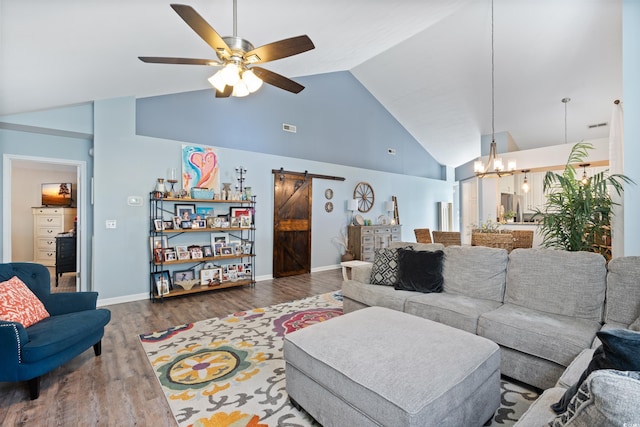 living area featuring a barn door, high vaulted ceiling, ceiling fan, a chandelier, and wood finished floors