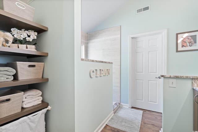 hall with wood finished floors, vaulted ceiling, and baseboards