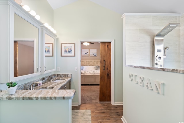 ensuite bathroom with wood finished floors, walk in shower, vaulted ceiling, baseboards, and a ceiling fan