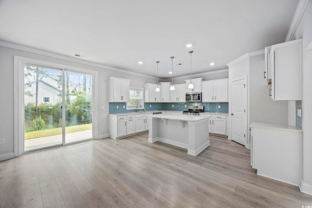 1303 Bermuda Grass Dr, Myrtle Beach, SC 29579 - kitchen featuring appliances with stainless steel finishes, a kitchen island, light countertops, ornamental molding, and light wood-style flooring