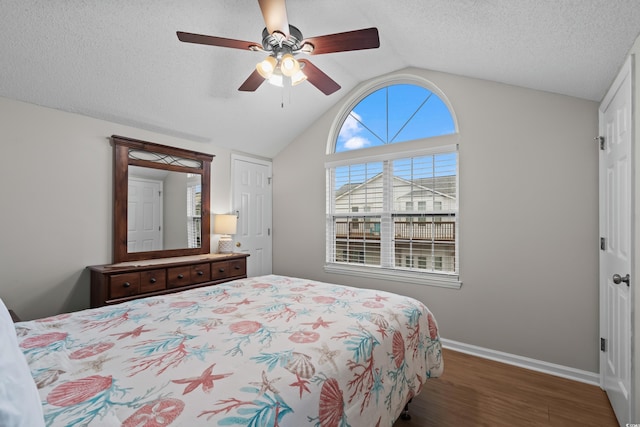 bedroom with lofted ceiling, wood finished floors, a closet, baseboards, and a ceiling fan