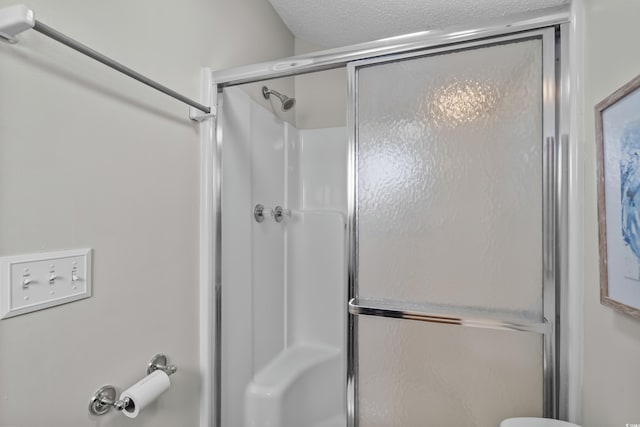 full bath featuring a shower with shower door and a textured ceiling