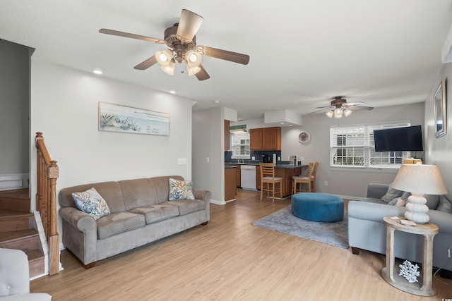 living room with ceiling fan, light wood-style floors, healthy amount of natural light, and baseboards
