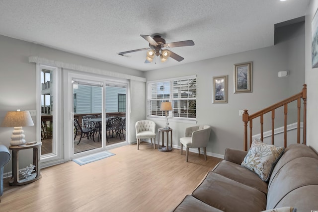living area with a ceiling fan, wood finished floors, baseboards, and a textured ceiling