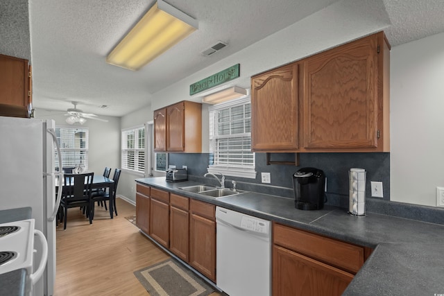 kitchen with white appliances, a sink, a textured ceiling, a ceiling fan, and light wood-style flooring