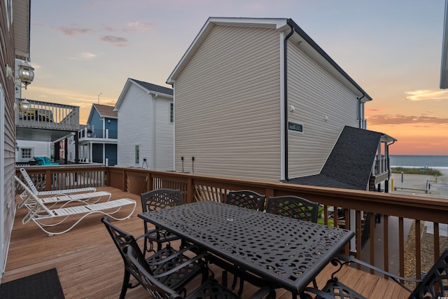 deck at dusk featuring outdoor dining space and a water view