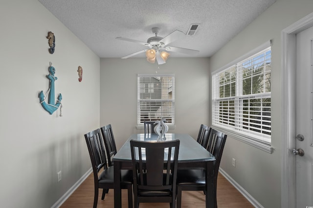 dining room featuring a textured ceiling, wood finished floors, a ceiling fan, and baseboards