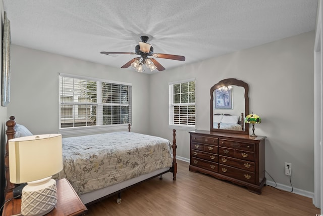 bedroom featuring baseboards, wood finished floors, a ceiling fan, and a textured ceiling