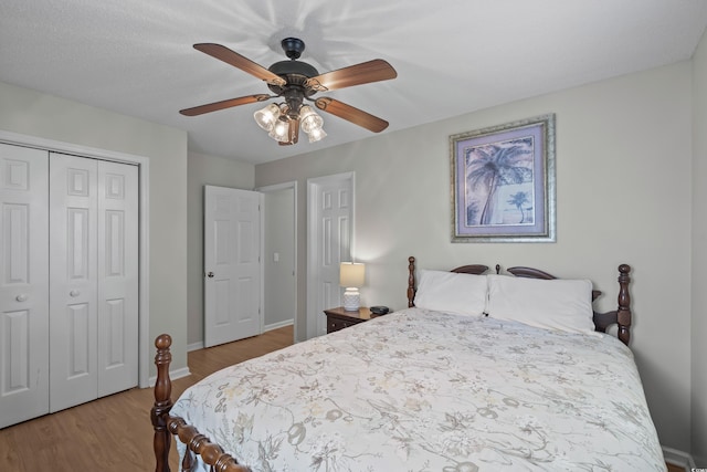 bedroom with wood finished floors, a closet, baseboards, and a ceiling fan