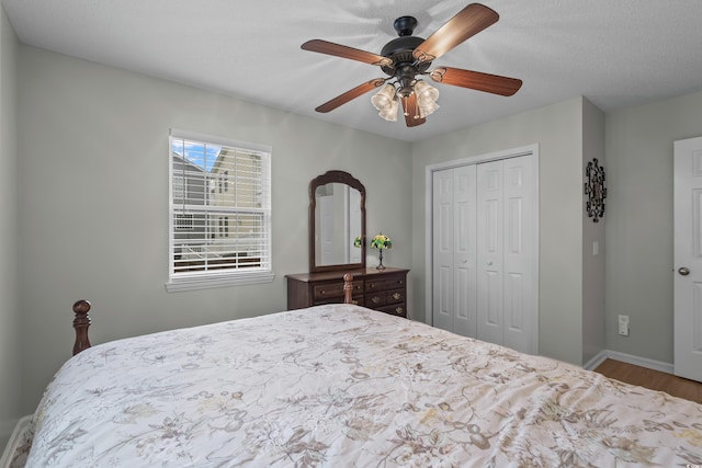 bedroom with wood finished floors, a closet, baseboards, and ceiling fan