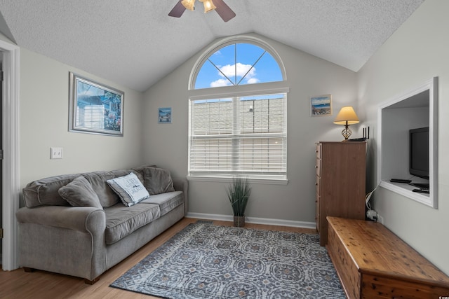 living area featuring lofted ceiling, a ceiling fan, wood finished floors, and a textured ceiling