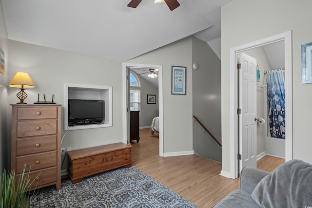 living room featuring a ceiling fan, vaulted ceiling, wood finished floors, and baseboards