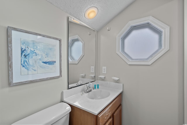 bathroom featuring a textured ceiling, toilet, and vanity