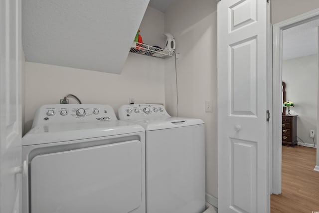 laundry room featuring washer and clothes dryer and light wood-style floors