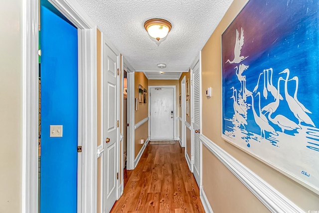corridor with a textured ceiling and wood finished floors