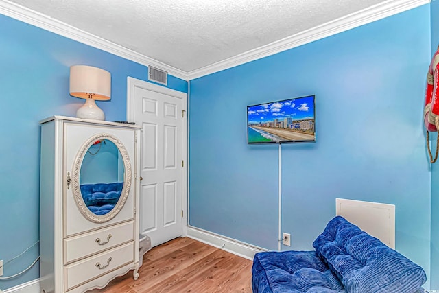 sitting room with ornamental molding, wood finished floors, a textured ceiling, and baseboards