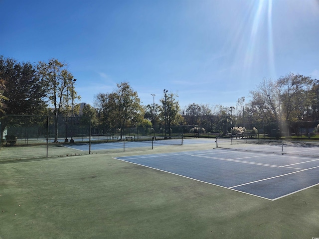 view of tennis court featuring fence and community basketball court