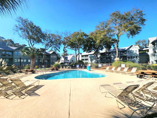 community pool with a residential view, fence, and a patio area