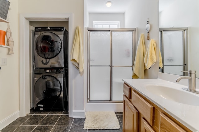 full bathroom featuring stacked washer and clothes dryer, tile patterned flooring, a stall shower, vanity, and baseboards