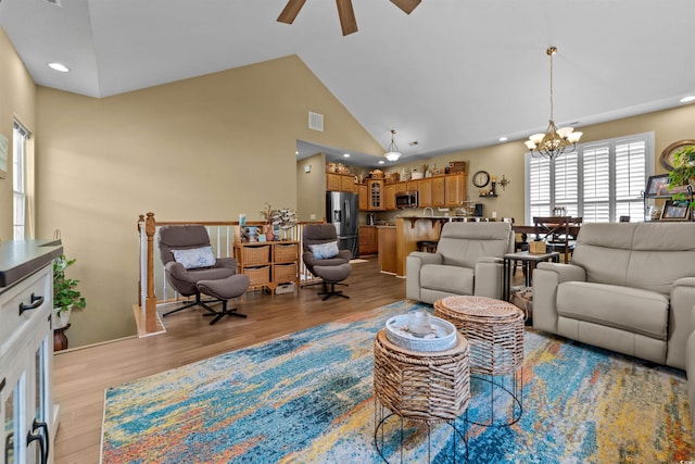 living area featuring a chandelier, plenty of natural light, a ceiling fan, light wood-type flooring, and high vaulted ceiling
