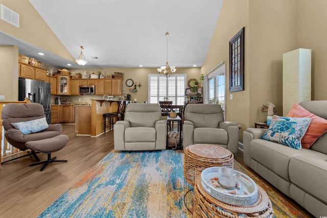 living area with high vaulted ceiling, a chandelier, light wood-type flooring, and recessed lighting