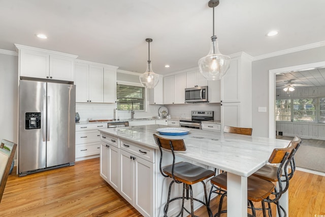 2604 S Bay St, Georgetown, SC 29440 - kitchen featuring stainless steel appliances, light wood-style floors, crown molding, white cabinetry, and backsplash
