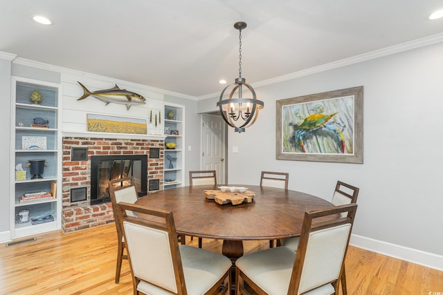 2604 S Bay St, Georgetown, SC 29440 - dining area with crown molding, light wood-style floors, baseboards, a chandelier, and a brick fireplace