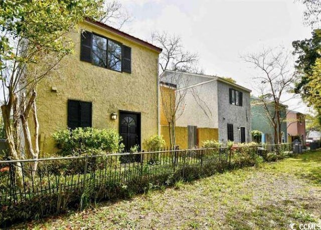 back of house featuring fence and stucco siding