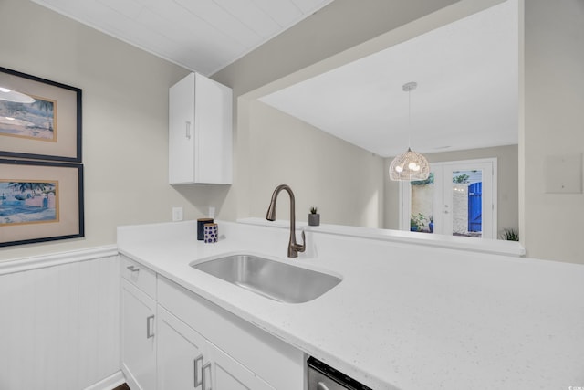 kitchen with a sink, white cabinetry, french doors, a wainscoted wall, and pendant lighting