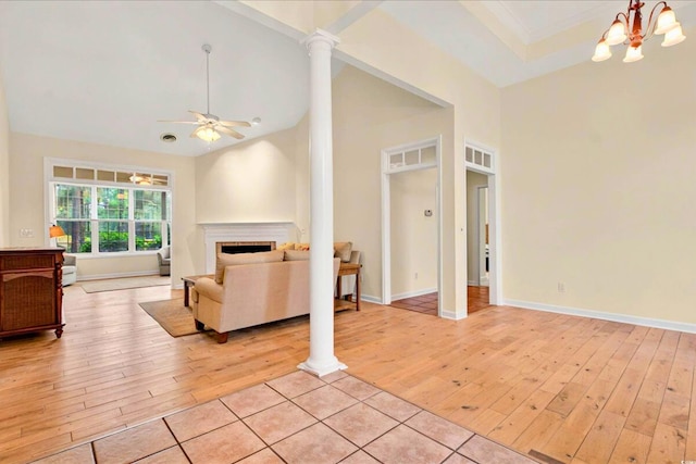 154 Windsor Cir SW, Ocean Isle Beach, NC 28469 - living area featuring light wood-style flooring, a ceiling fan, a chandelier, a fireplace, and decorative columns