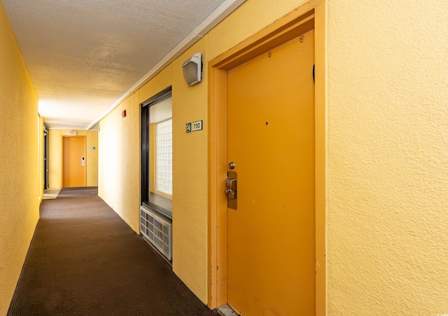 corridor with a textured wall, a textured ceiling, and crown molding