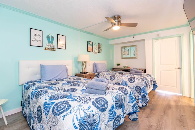 bedroom with wood finished floors, crown molding, a textured ceiling, and a ceiling fan