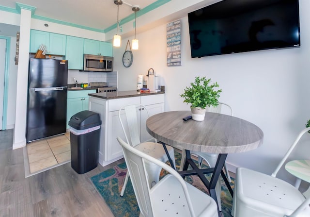 kitchen with freestanding refrigerator, stainless steel microwave, a peninsula, blue cabinetry, and a sink