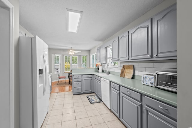kitchen featuring white appliances, gray cabinets, a sink, light tile patterned floors, and ceiling fan