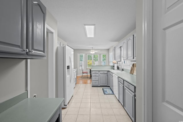 kitchen featuring gray cabinets, white appliances, light tile patterned floors, light countertops, and a sink