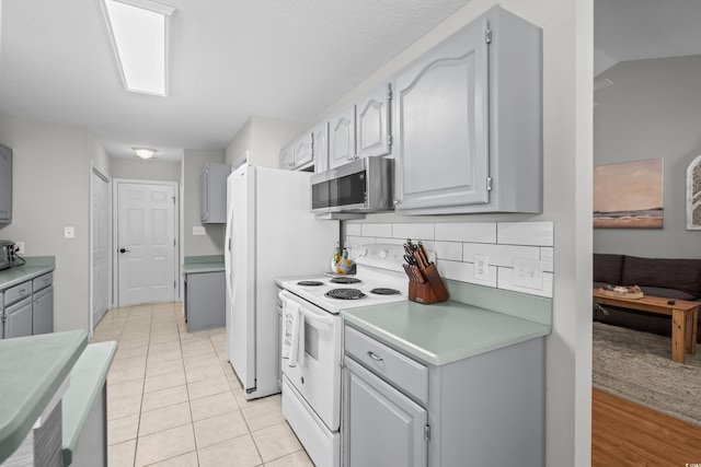 kitchen featuring stainless steel microwave, white range with electric cooktop, gray cabinets, light countertops, and light tile patterned floors