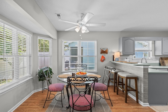 dining room with light wood-style flooring, ceiling fan, and baseboards