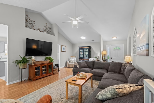 living area featuring lofted ceiling, light wood-style floors, and a ceiling fan