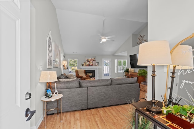 living room featuring high vaulted ceiling, a ceiling fan, wood finished floors, and a fireplace