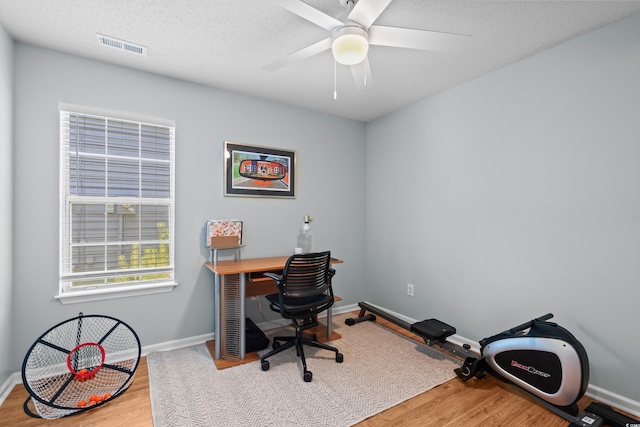 home office featuring wood finished floors, baseboards, ceiling fan, and a textured ceiling