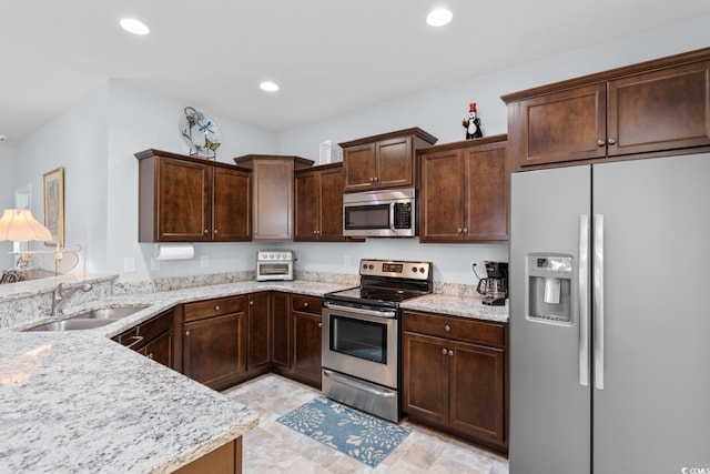 kitchen featuring stainless steel appliances, a sink, dark brown cabinetry, recessed lighting, and light stone counters